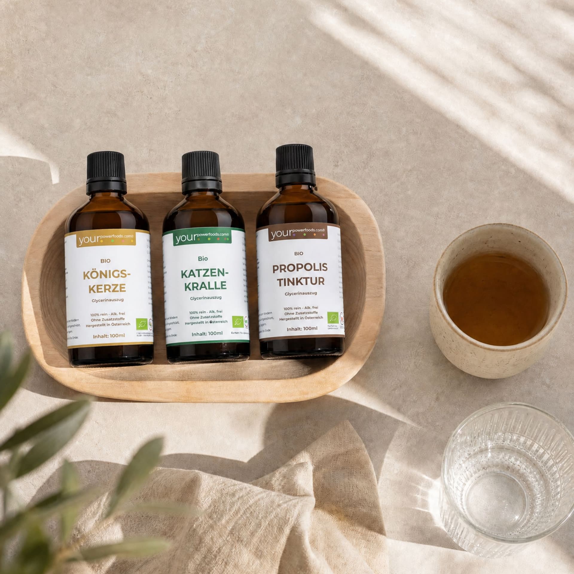 Immun Balance Bundle – Königskerze, Katzenkralle & Propolis: drei Braunglas-Fläschchen à 100 ml in Holzschale, daneben Tasse mi